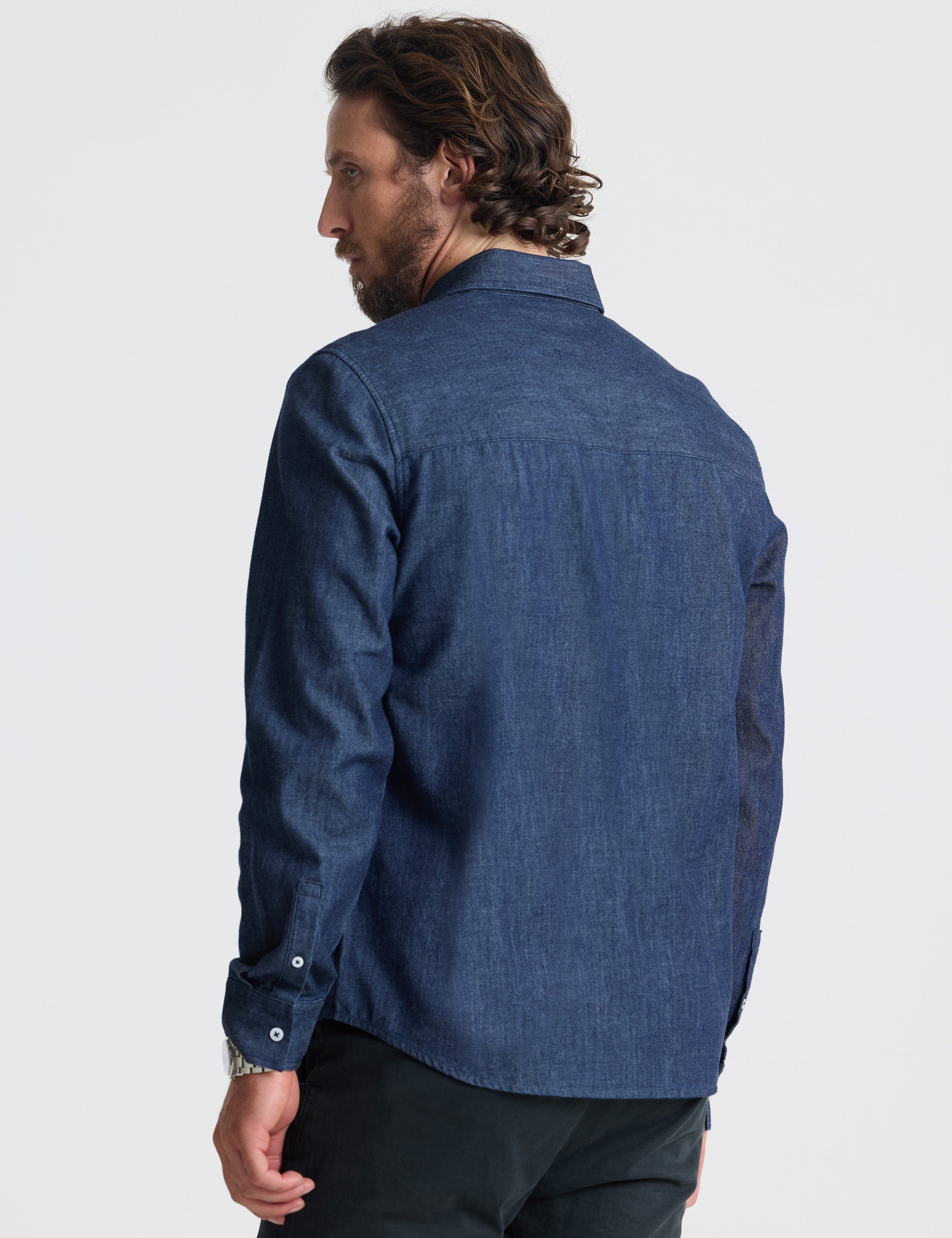 Rear view of man wearing Alder Chambray Button-Down in Dark Blue from AETHER Apparel.