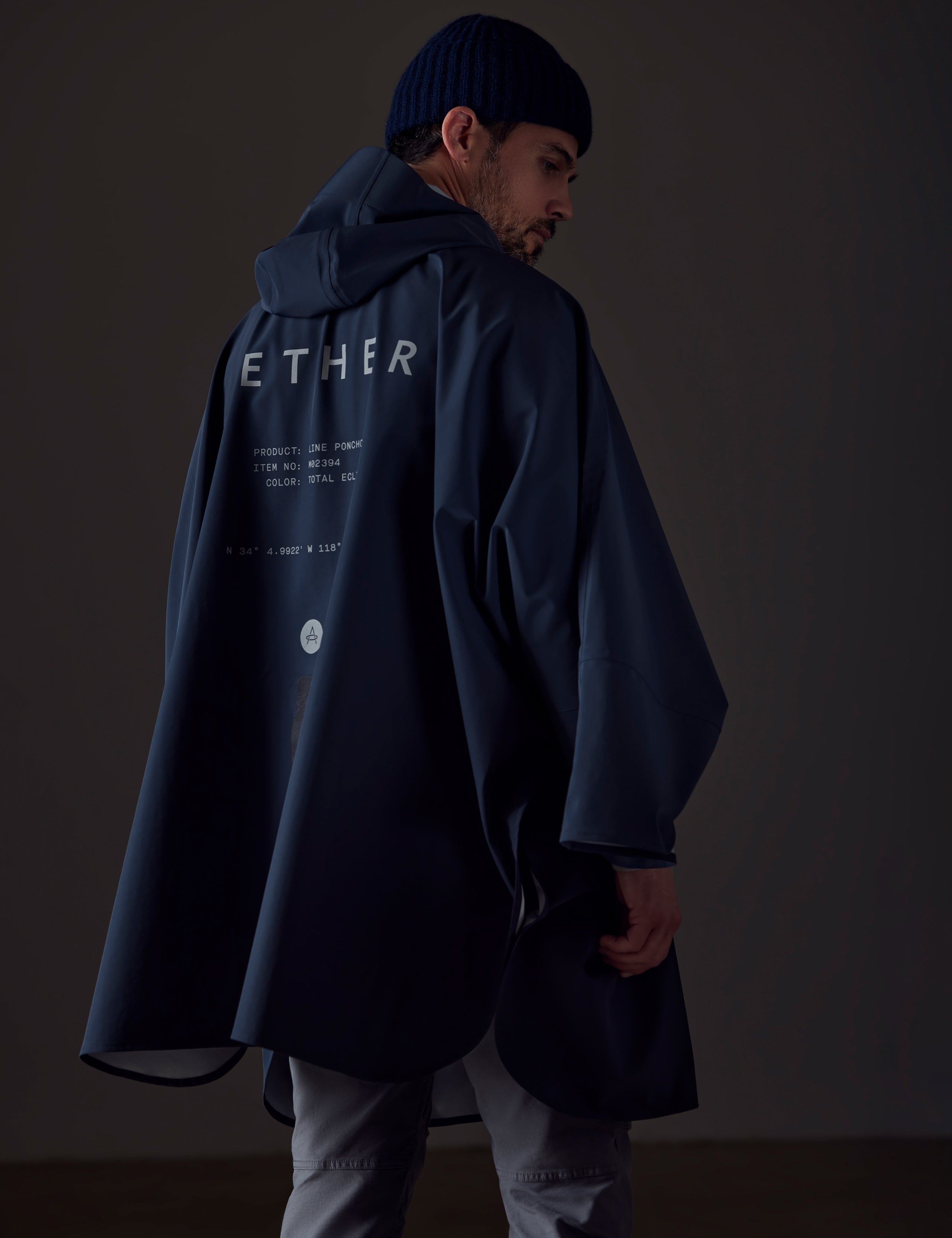Back view of man wearing the Line Poncho in Total Eclipse dark blue from AETHER Apparel.