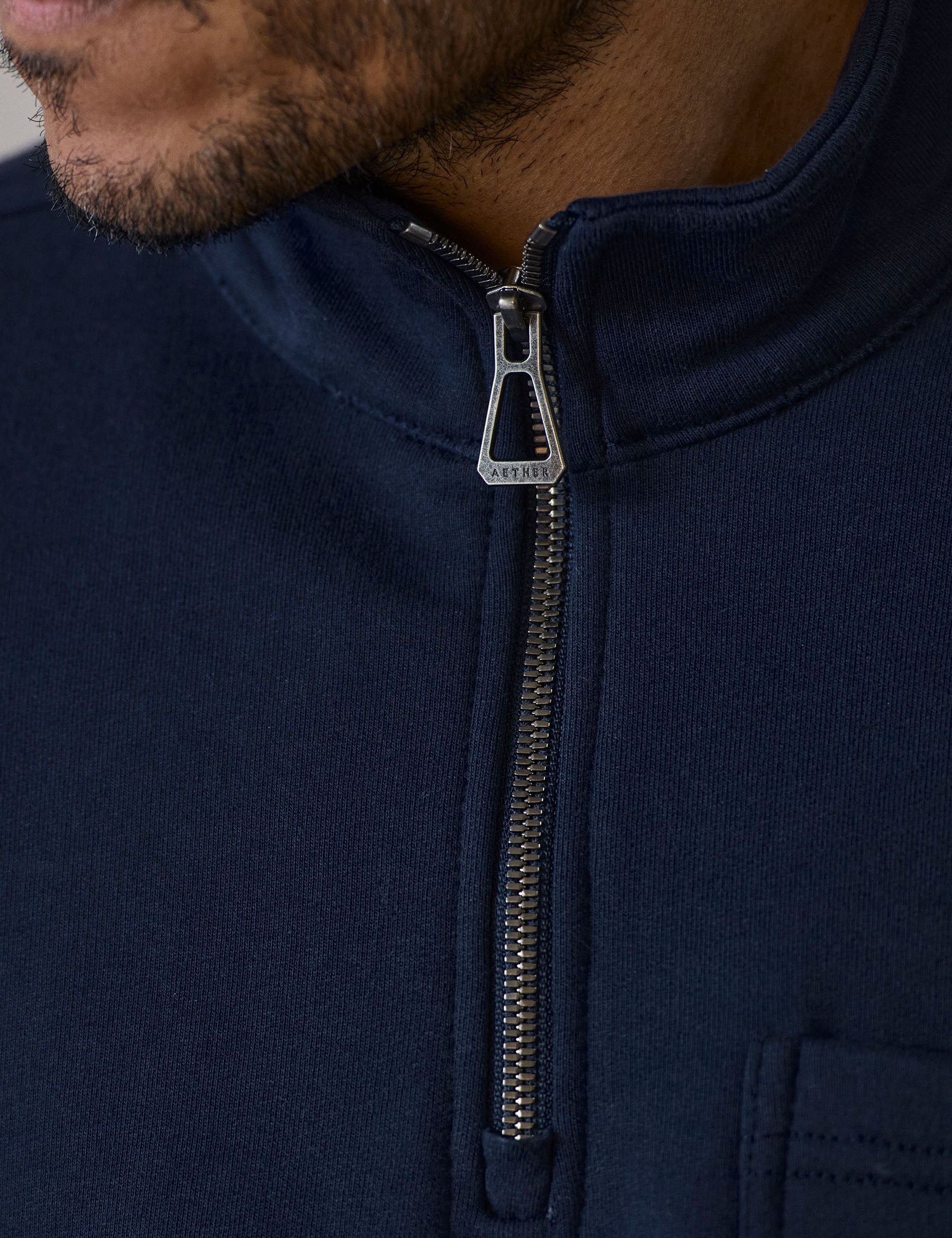 Closeup detailed view of the half-zip center-front closure on the Monte Half-Zip Sweatshirt in Total Eclipse dark blue from AETHER Apparel.